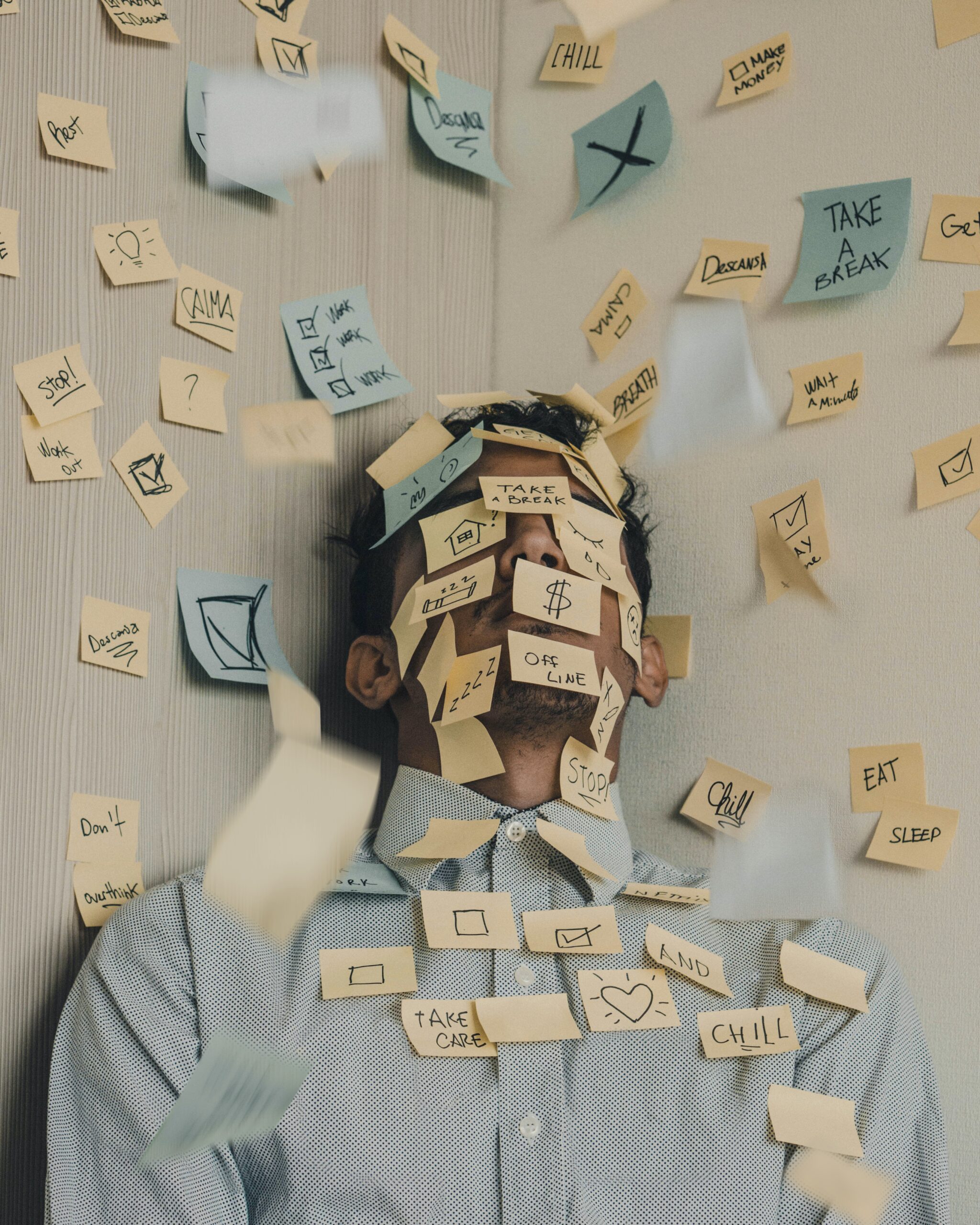 A young man lies on the ground, his face covered in sticky notes