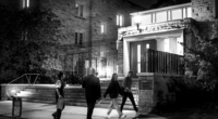 Students walking on a dark college campus towards a lit building