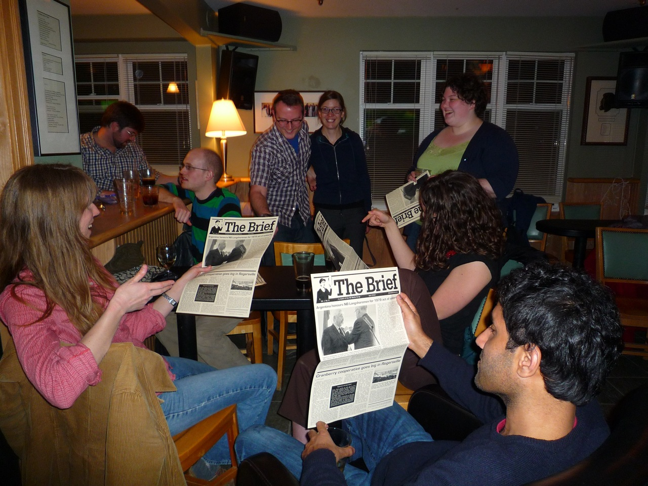 A group of people gathered together, some reading the Brief newsletter  