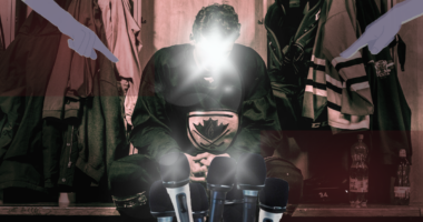 Hockey player surrounded by mics in a locker room.