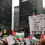 At a pro-Palestine rally in Toronto, a sign reads, "THE MEDIA IS BOUGHT BUT WE ARE NOT."