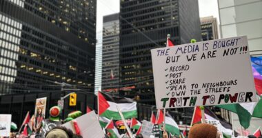 At a pro-Palestine rally in Toronto, a sign reads, "THE MEDIA IS BOUGHT BUT WE ARE NOT."