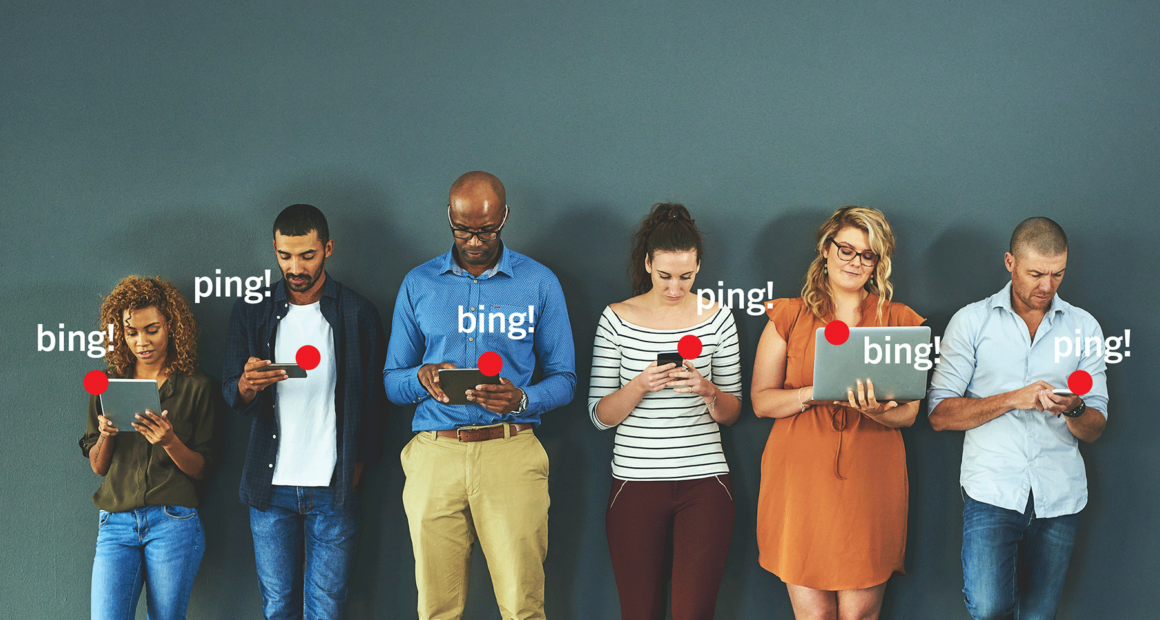 A group of people in a line looking their electronic devices