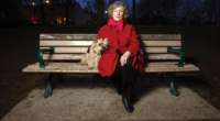 Stevie Cameron sits on a park bench with her dog at night