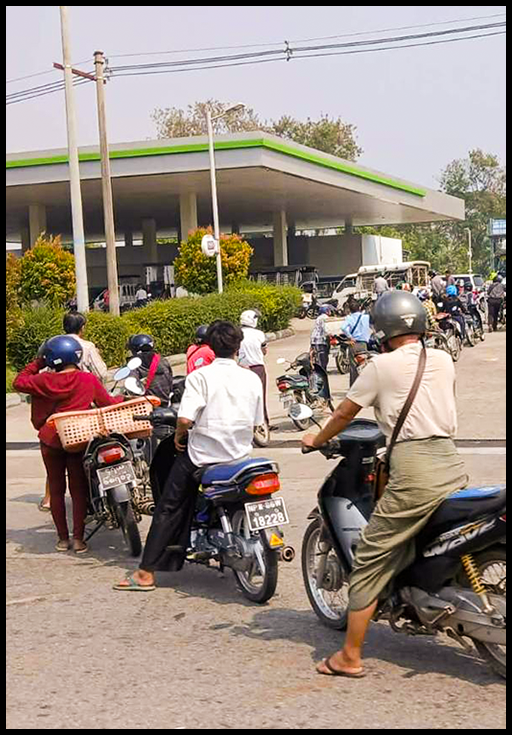 People sitting on motorbikes lined up in front of a gas station.